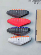 Four Nike Mind slide soles shown from the side in black, red, dark blue-gray, and white, with rows of circular outsole nodes.