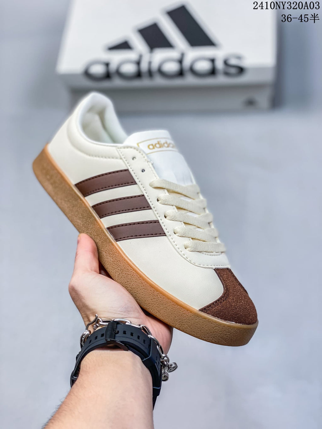 Angled side view of the white and brown Adidas low-top sneaker with a gum-colored outsole.