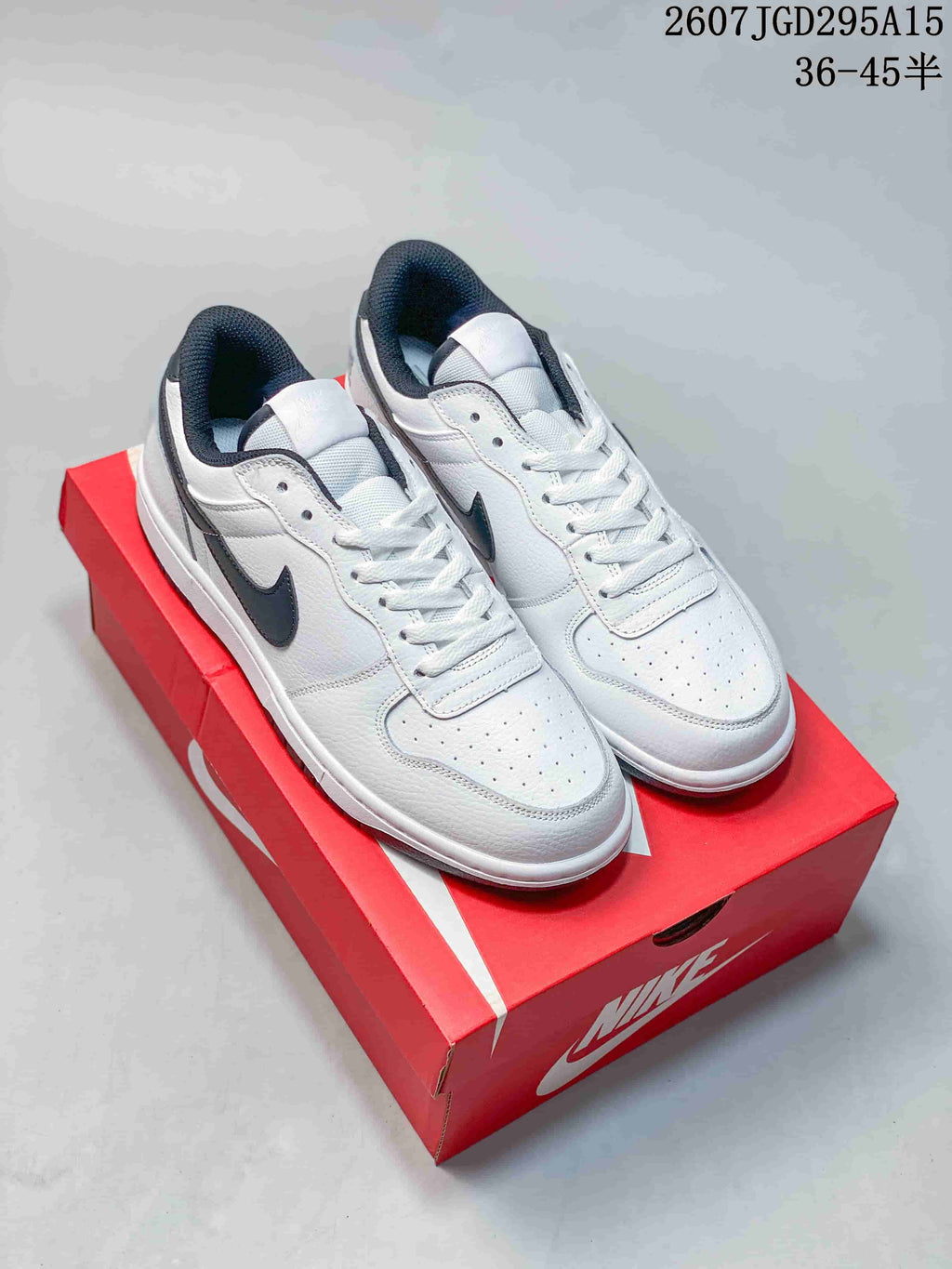 Pair of white and black Nike SB Dunk Low Pro sneakers displayed on a red shoebox; visible overlay reads style code 2607TGD295A15 and size range 36–45 half sizes.