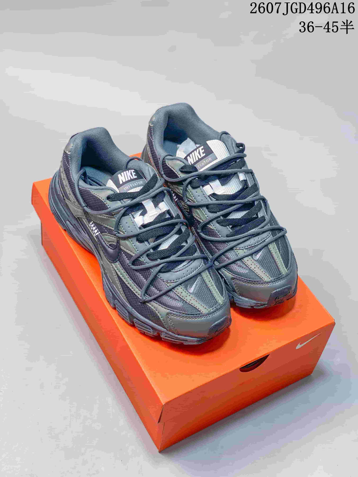Pair of gray and olive Nike Initiator sneakers displayed on an orange shoe box.