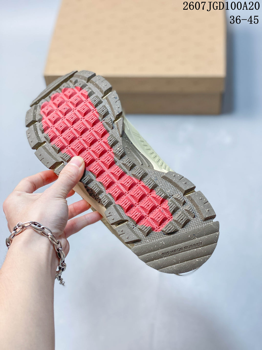 Close-up of the rugged outsole showing gray traction sections and a contrasting red center tread.