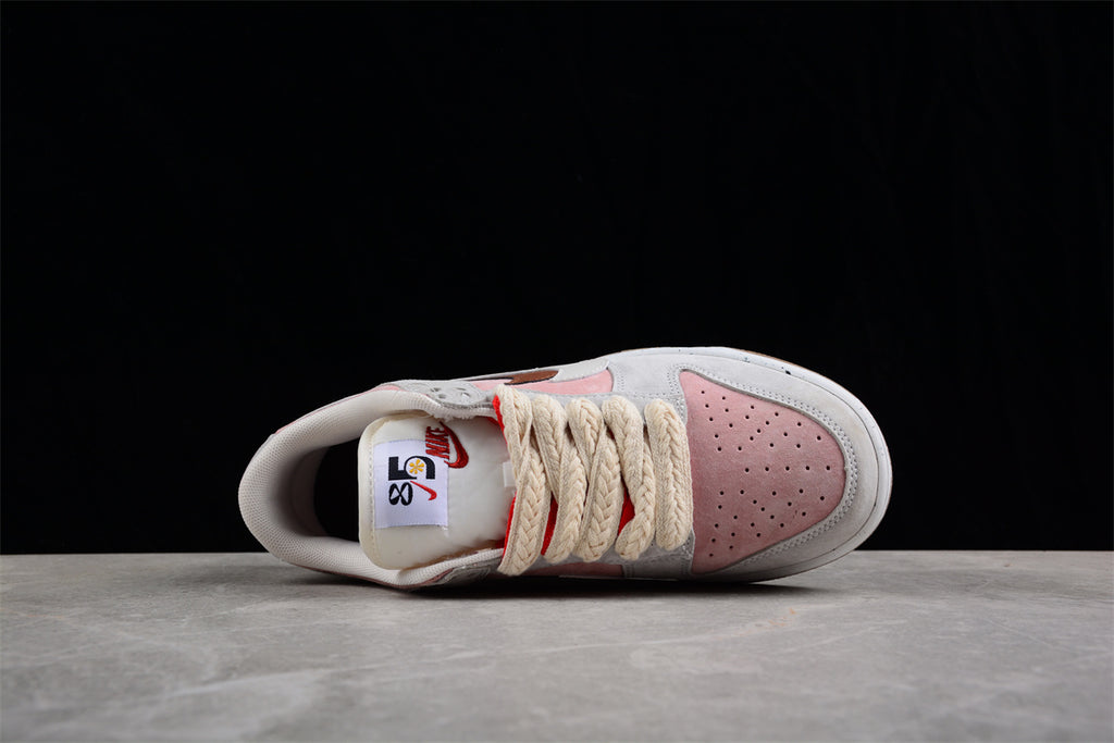 Top view showing the perforated pink toe box, cream braided laces, and tongue labels.