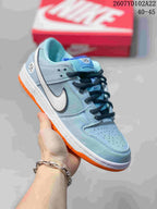 Light blue Nike SB Dunk Low Pro sneaker with a white Swoosh, dark laces and orange outsole.