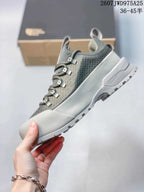 Side view of the gray trail sneaker showing the layered upper, lace system, protective toe area and lugged outsole.