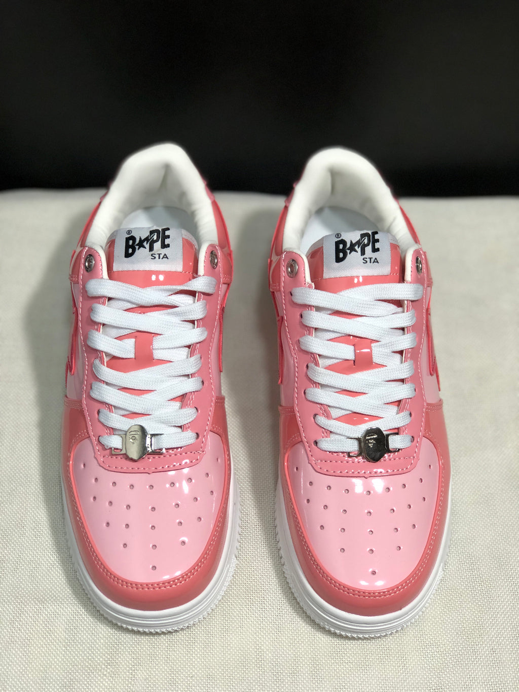 Front view of the pair showing pink toe panels, white laces, metal lace hardware, and white soles.