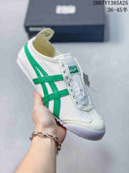 White Onitsuka Tiger slip-on sneaker with bright green side stripes and a white outsole.
