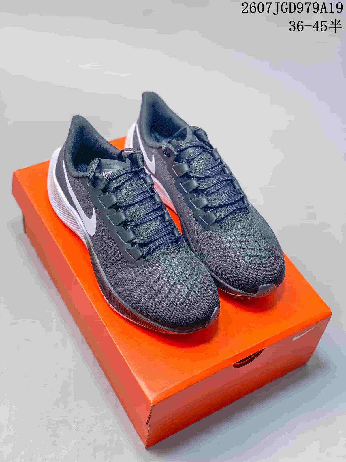 Pair of dark Nike Pegasus 37 sneakers displayed on an orange shoebox, with the source size range and style code overlaid at the top.