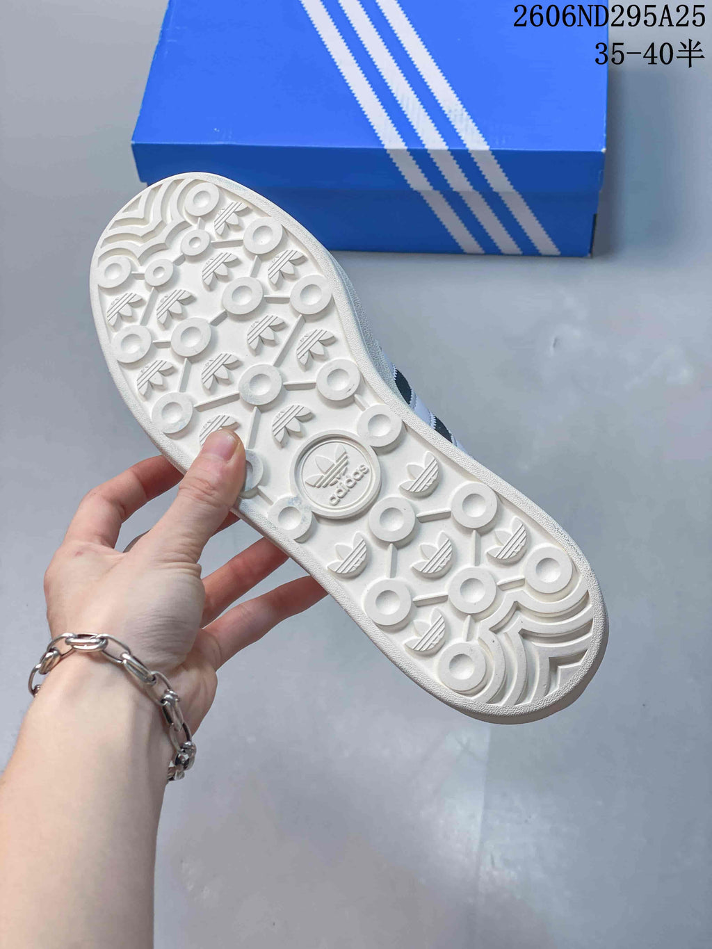 Underside of the sneaker showing a white patterned outsole with circular traction details and Trefoil motifs.