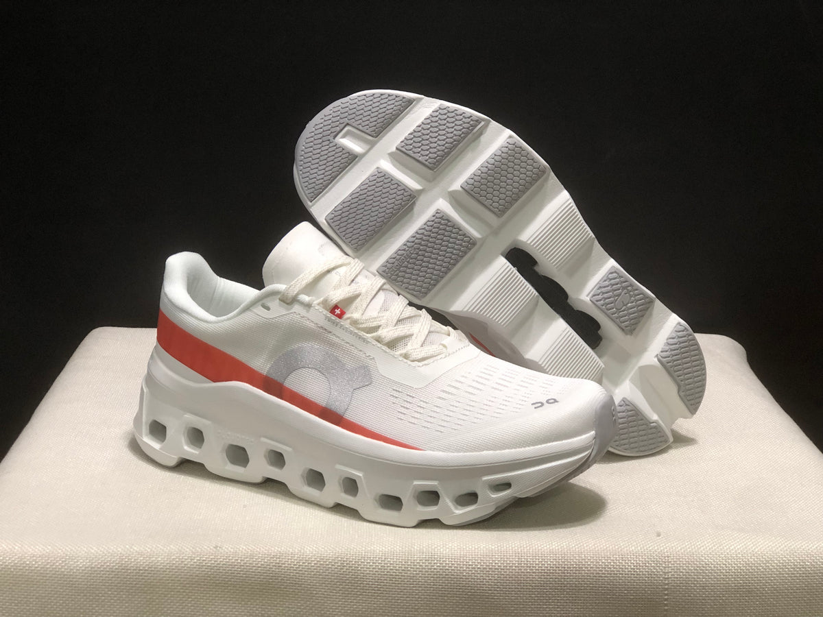 White and coral Cloudmonster 1 sneakers shown with one outsole facing upward.