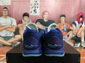 Rear view of deep blue basketball shoes with aqua outsole accents and a signature on the heels