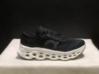 Side view highlighting the black upper, tonal On branding, and white midsole cavities.