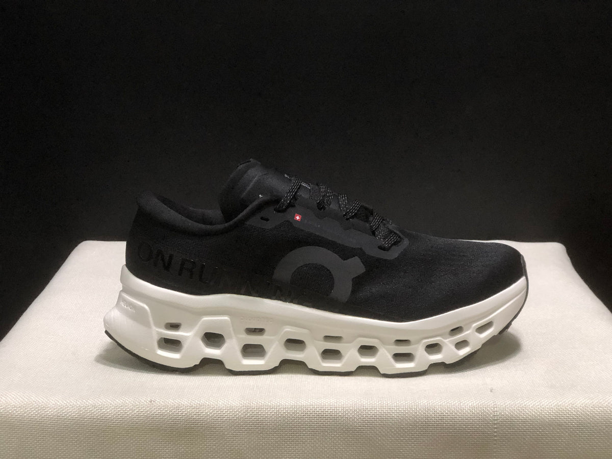 Side view highlighting the black upper, tonal On branding, and white midsole cavities.