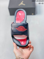 Top view of one slide showing the red textured footbed, black upper, and red Jordan Wings emblem.