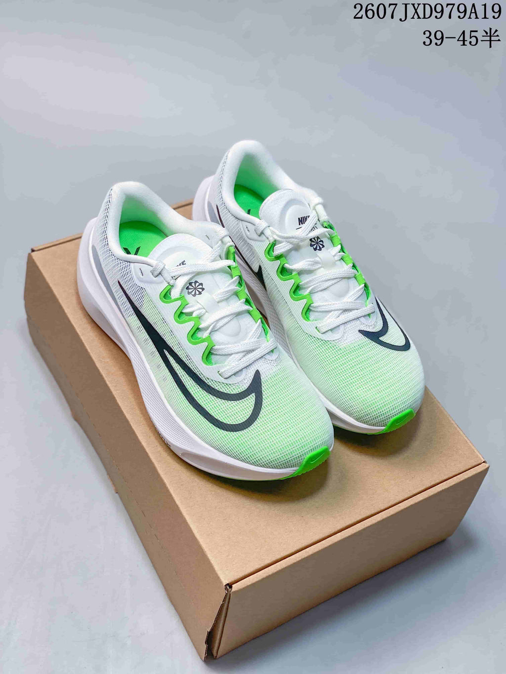 Pair of white Nike running sneakers with green accents and black side branding displayed on a shoebox.