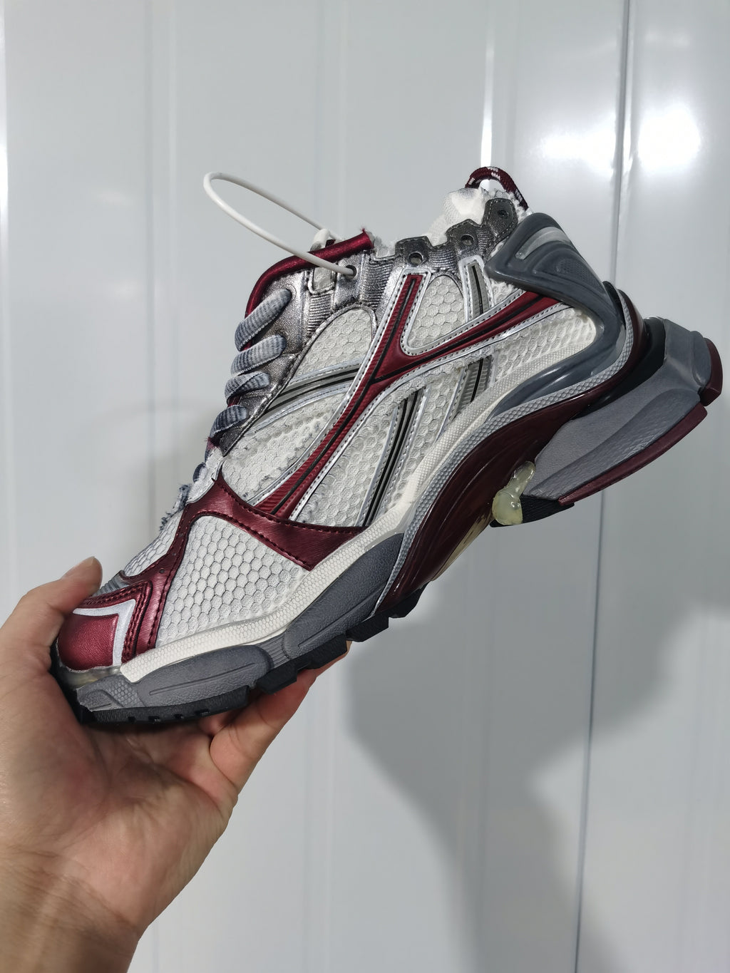 Angled view of the Puma Runner sneaker showing the textured panels, wine-red overlays, gray heel, and outsole.