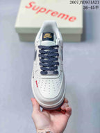 Top view showing the perforated white toe box, navy patterned laces, tongue branding and red stitching detail.