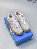 Pair of light-gray adidas Gazelle Bold sneakers displayed on a blue adidas shoebox, showing pink accents and a raised gum-colored sole.