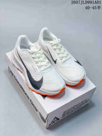 White Nike ACG trail shoes with dark accents and bright orange outsole details