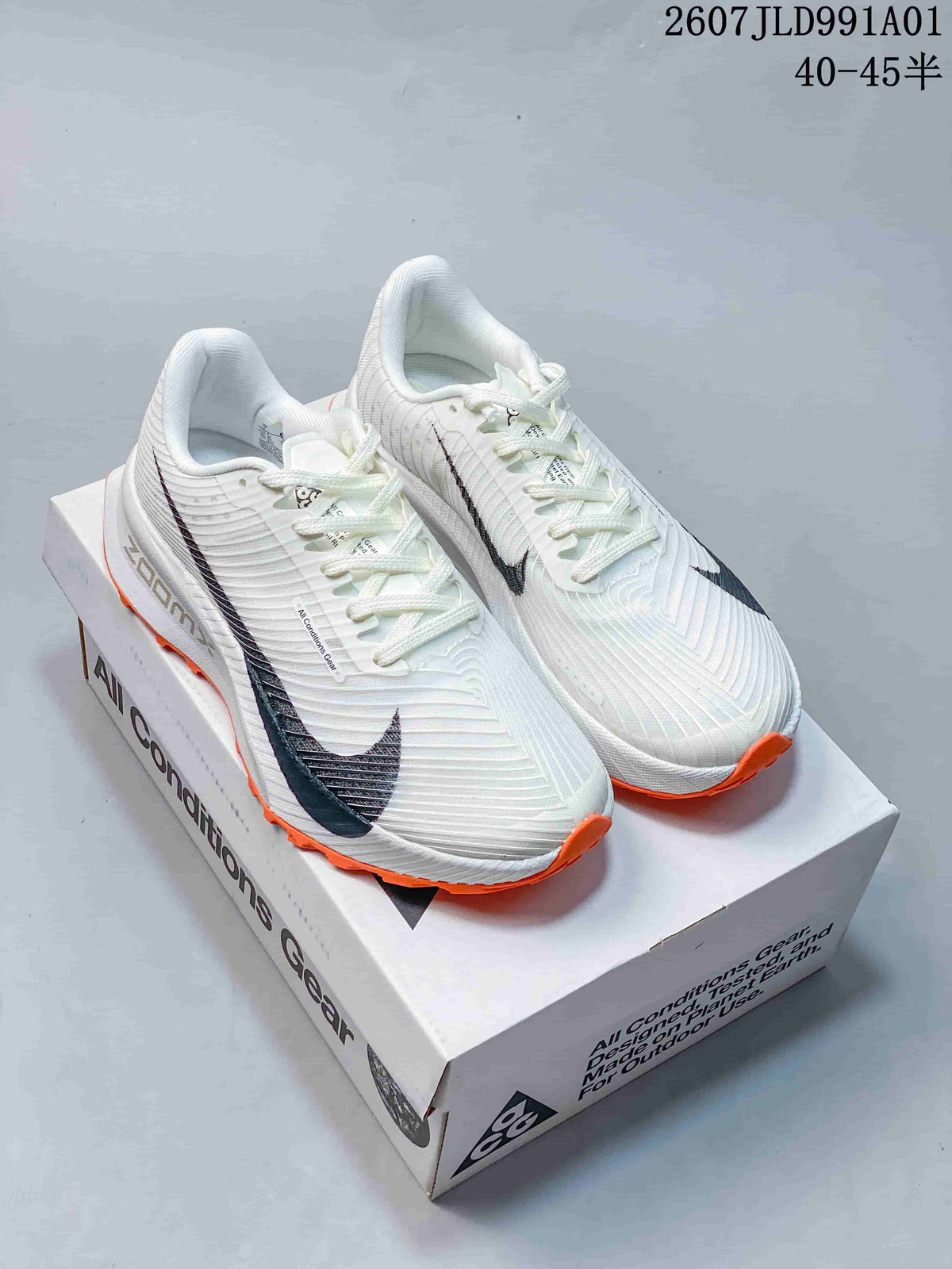 White Nike ACG trail shoes with dark accents and bright orange outsole details