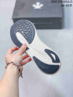 Underside view of a white sneaker showing the dark textured outsole and directional tread pattern.