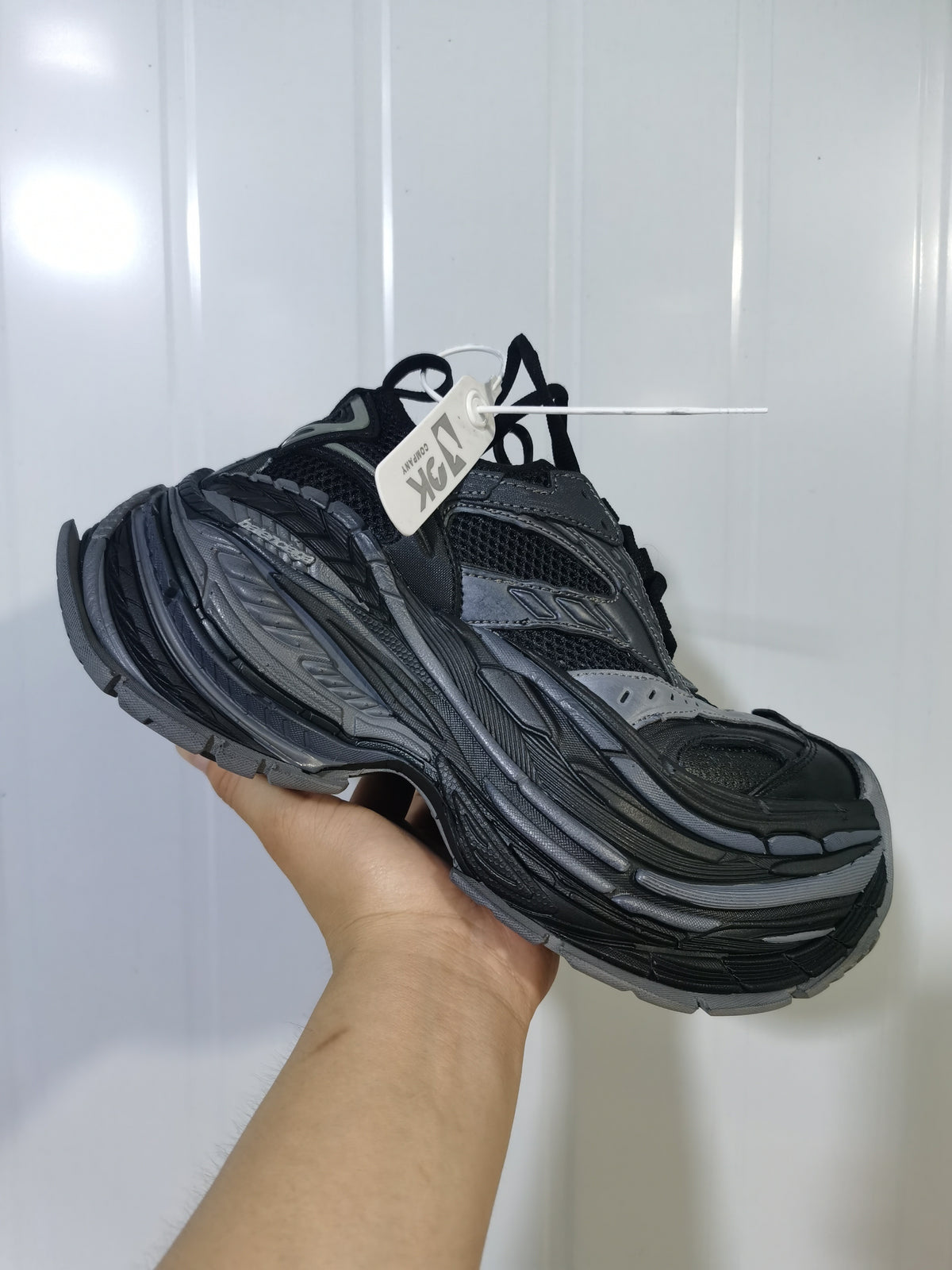 Angled view of the dark grey 1011 sneaker showing the toe, laces, mesh upper and layered outsole.