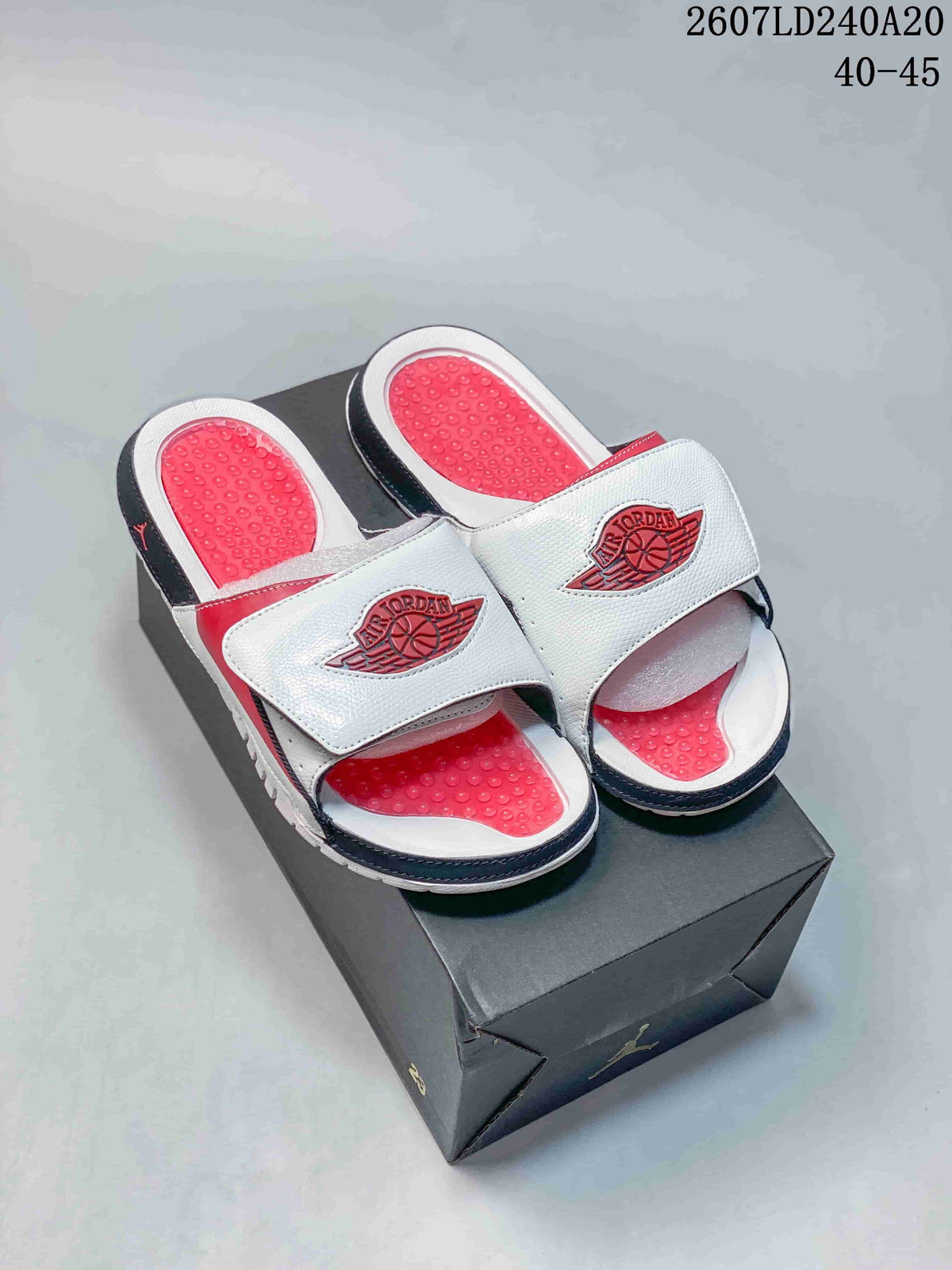 Pair of white, red, and black Jordan slides displayed on a black shoebox; image text shows style code 2607LD240A20 and sizes 40–45.