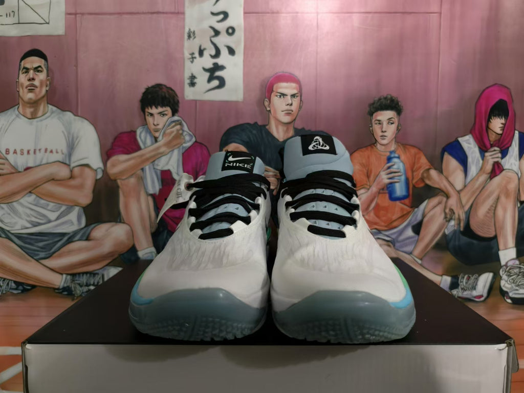 Front view of white Nike basketball shoes with black laces and blue-green toe accents.