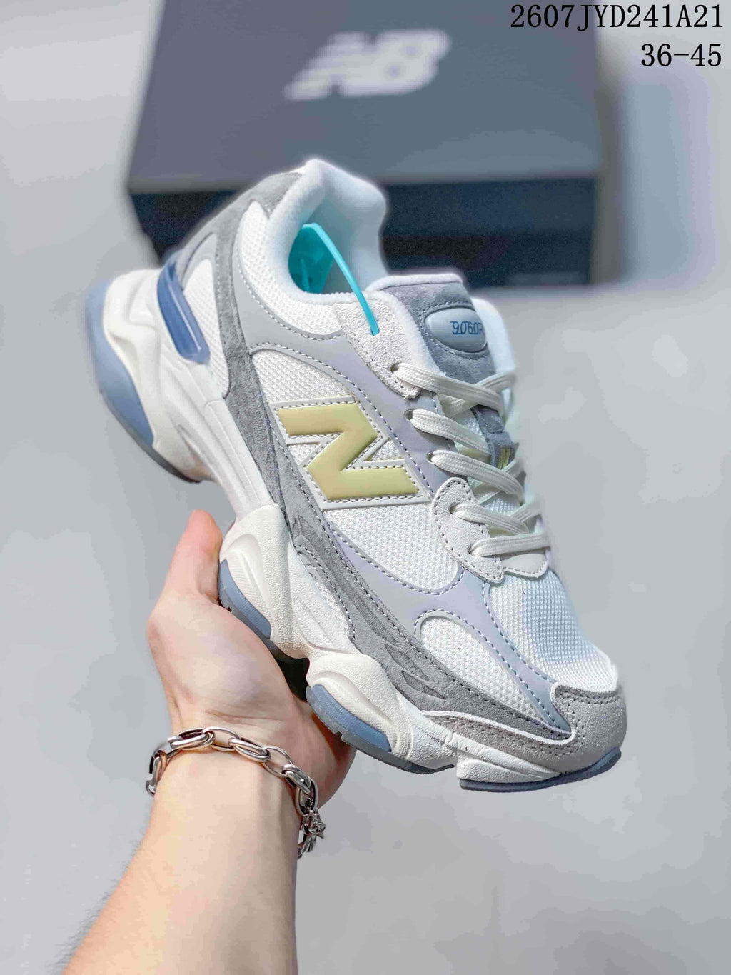 Angled side view of a New Balance 9060 sneaker showing the layered upper, yellow branding, blue heel accent and sculpted outsole.