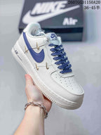 Close-up of a white Nike low-top sneaker with blue Swoosh branding, blue laces, and gold decorative accents.