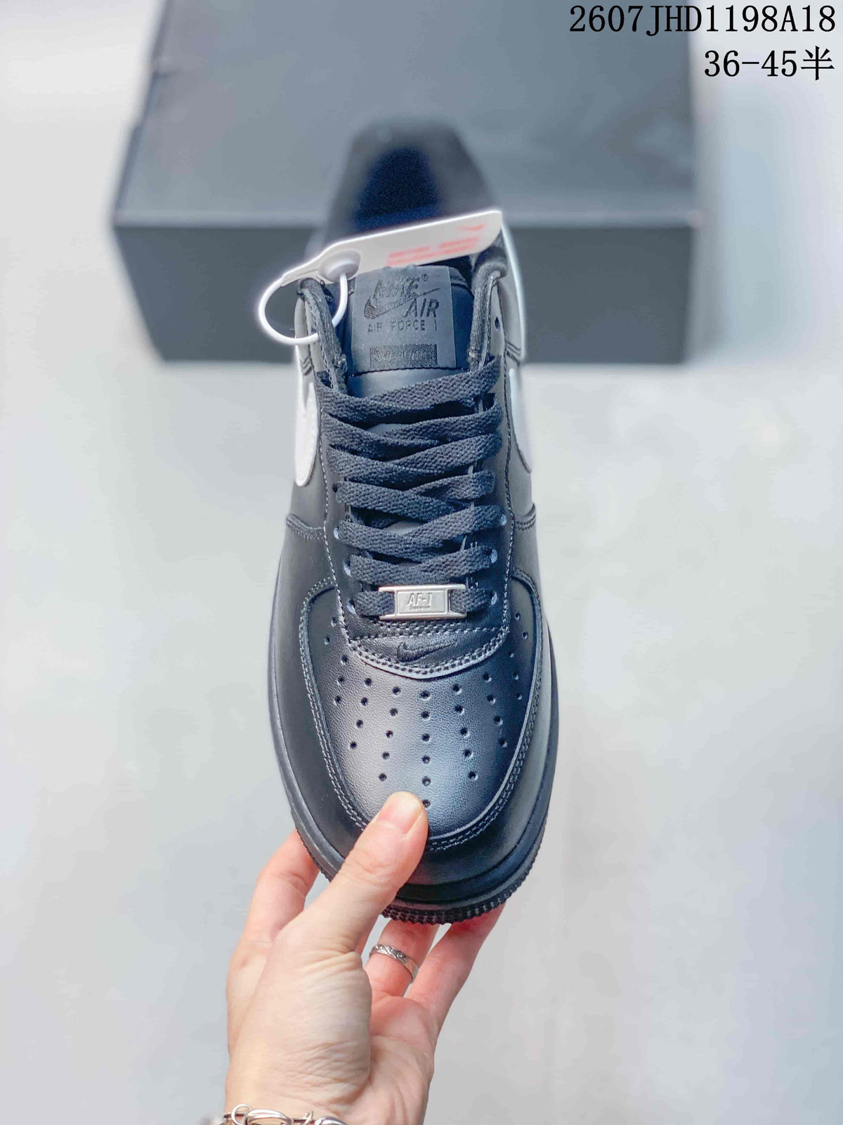 Top view of a black low-top sneaker showing black laces, a perforated toe box, tongue branding, and a small lace accessory; image text shows style code 2607JHD1198A18 and sizes 36–45.5.