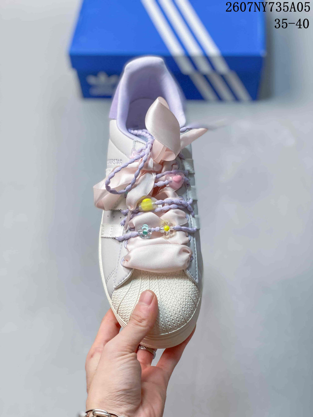 Top view showing the shell toe, pink ribbon laces, lavender cords, and colorful bead decorations.