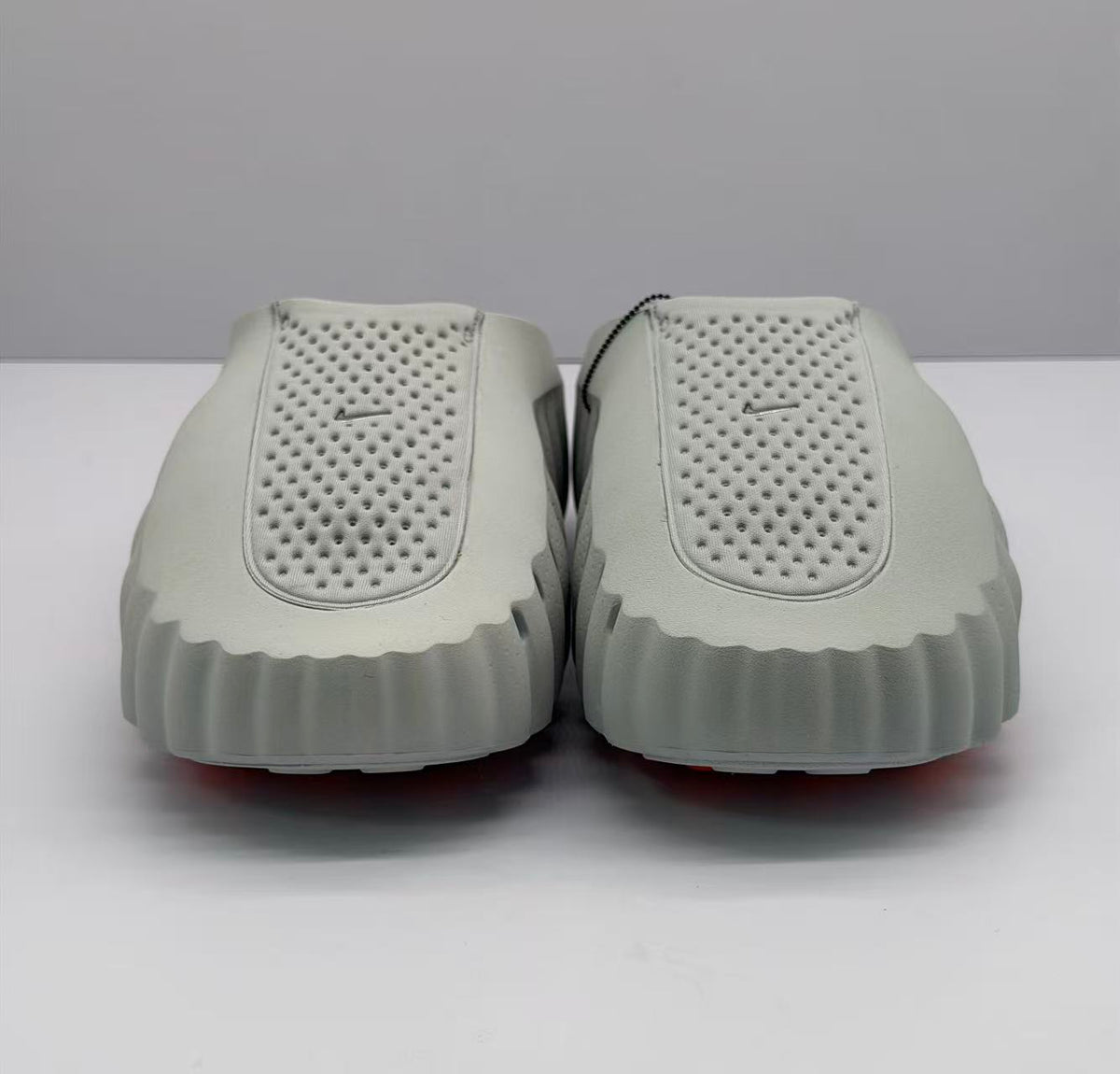 Front view of the pair of gray slide sandals showing the perforated uppers and rounded sculpted toes.