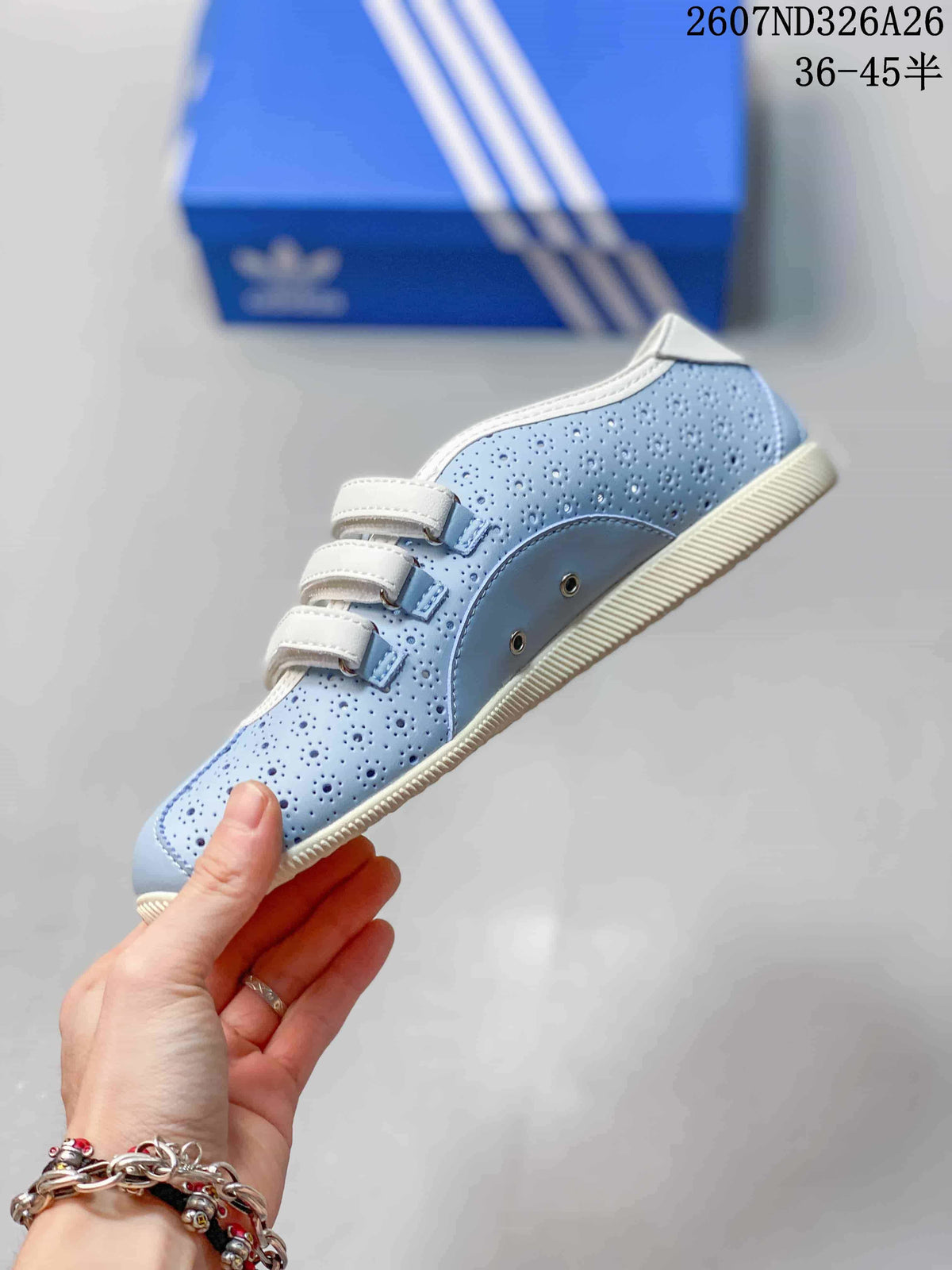 Side view showing the light blue perforated upper, three white strap closures, metal-tone hardware and cream-colored sole.