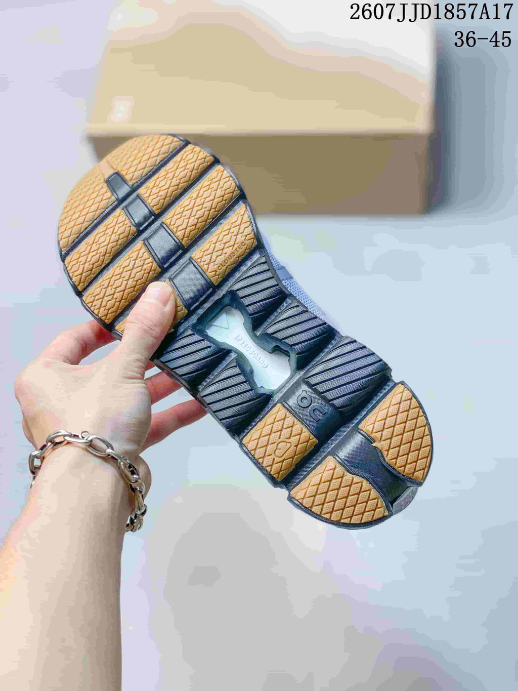 Close-up of the sneaker outsole showing segmented dark sole sections and tan-colored traction areas; background text shows size range 36–45.