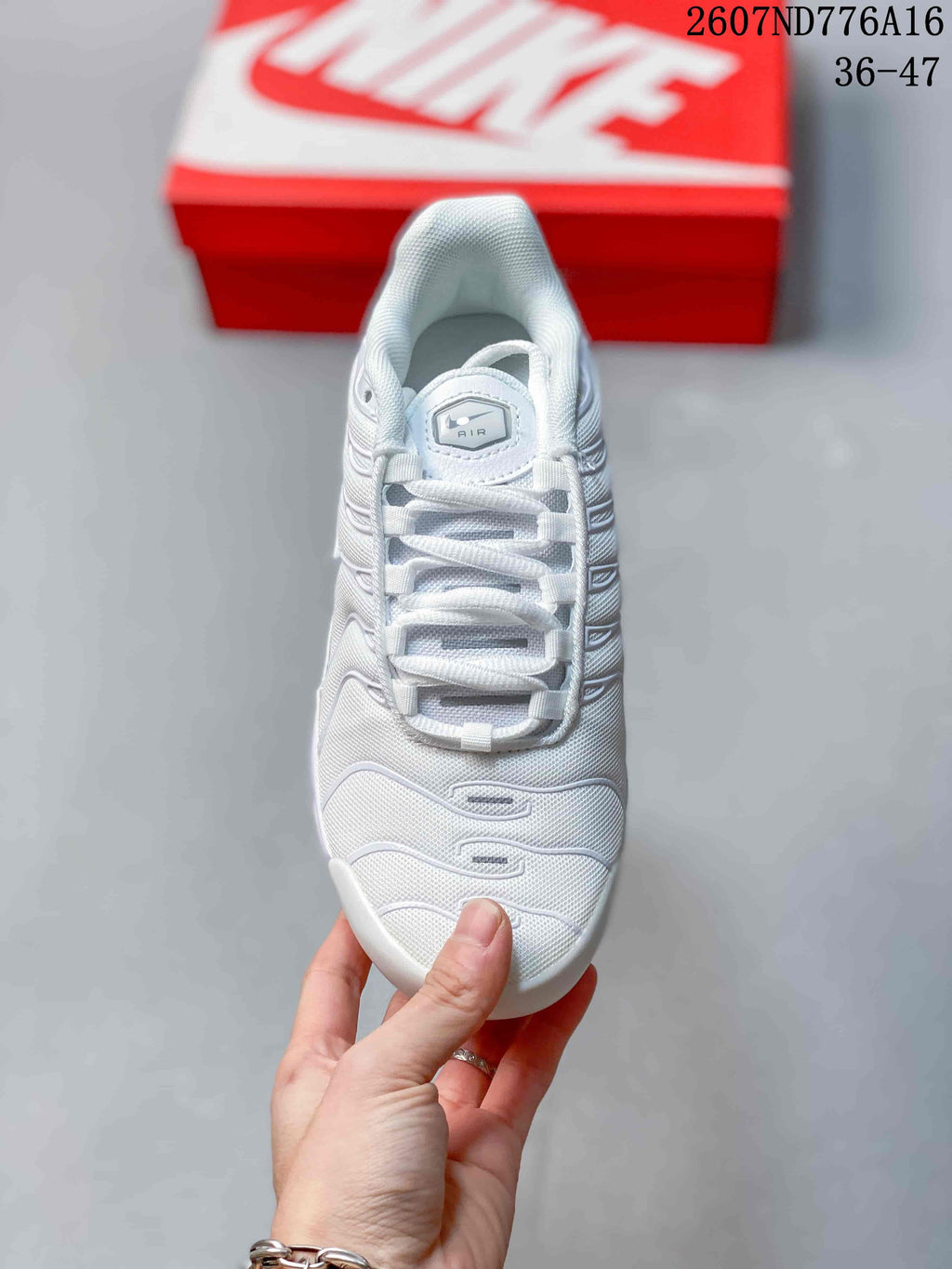 Top view of a white Nike Air Max Plus sneaker showing the laces, padded collar and layered upper panels; style code 2607ND776A16 and size range 36–47 are overlaid.