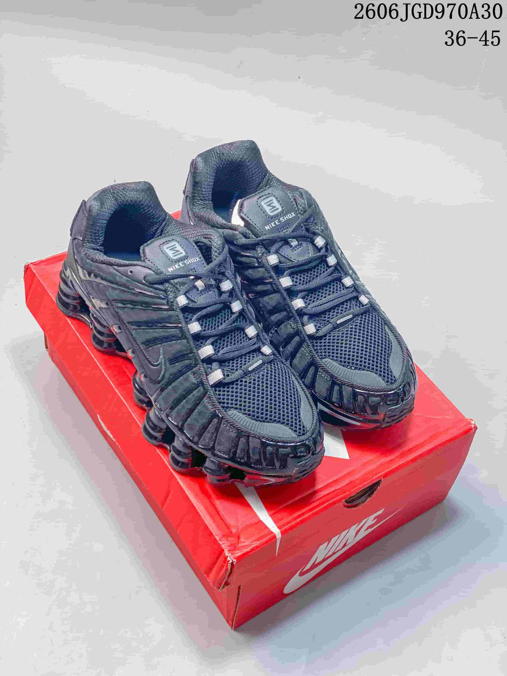 Pair of dark Nike Shox TL low-top sneakers on a red shoe box