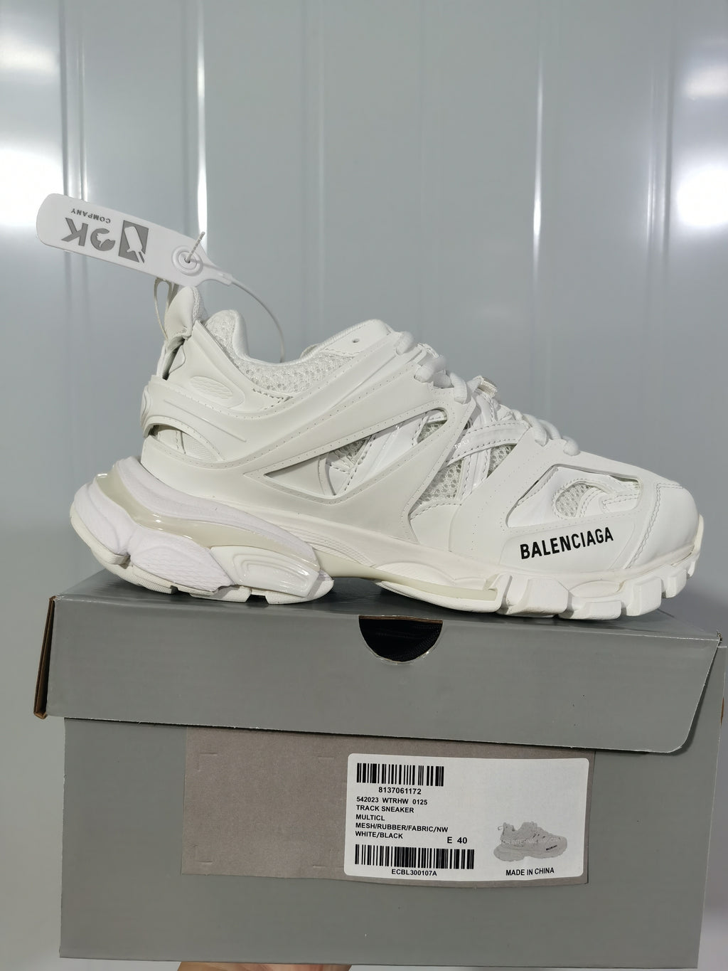Side view of a white Balenciaga Track sneaker resting on its box, with the box label identifying Track Sneaker 0125, White/Black and EU 40.