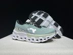 Side and outsole view of the pale green running shoes with black-and-white tread sections.