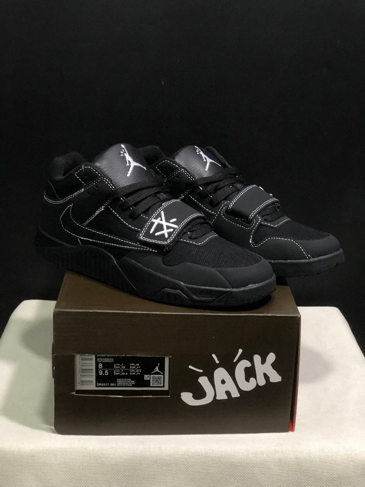 Pair of black Jordan Jumpman Jack sneakers displayed on a branded box; a size label is visible on the box.