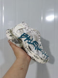 White and blue Balenciaga Runner sneaker held in hand, showing layered panels, mesh sections, and sculpted sole details.