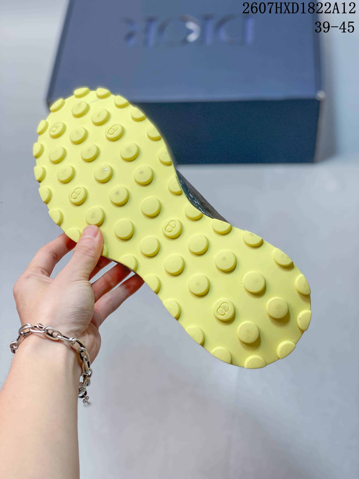 Close-up of the yellow lugged outsole with raised circular traction elements and Dior-style logo details.