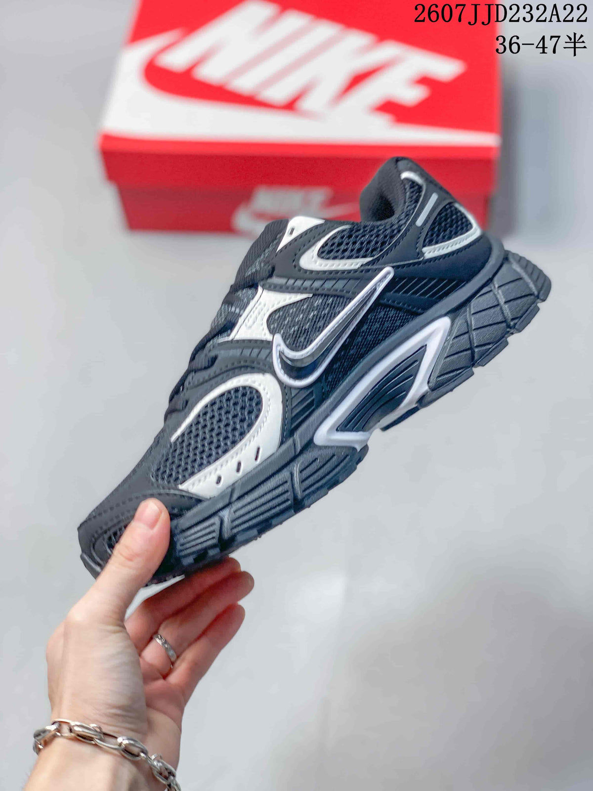 Side profile of a black and white Nike V5 RNR sneaker showing the mesh upper, contrast overlays, side branding, and chunky outsole.