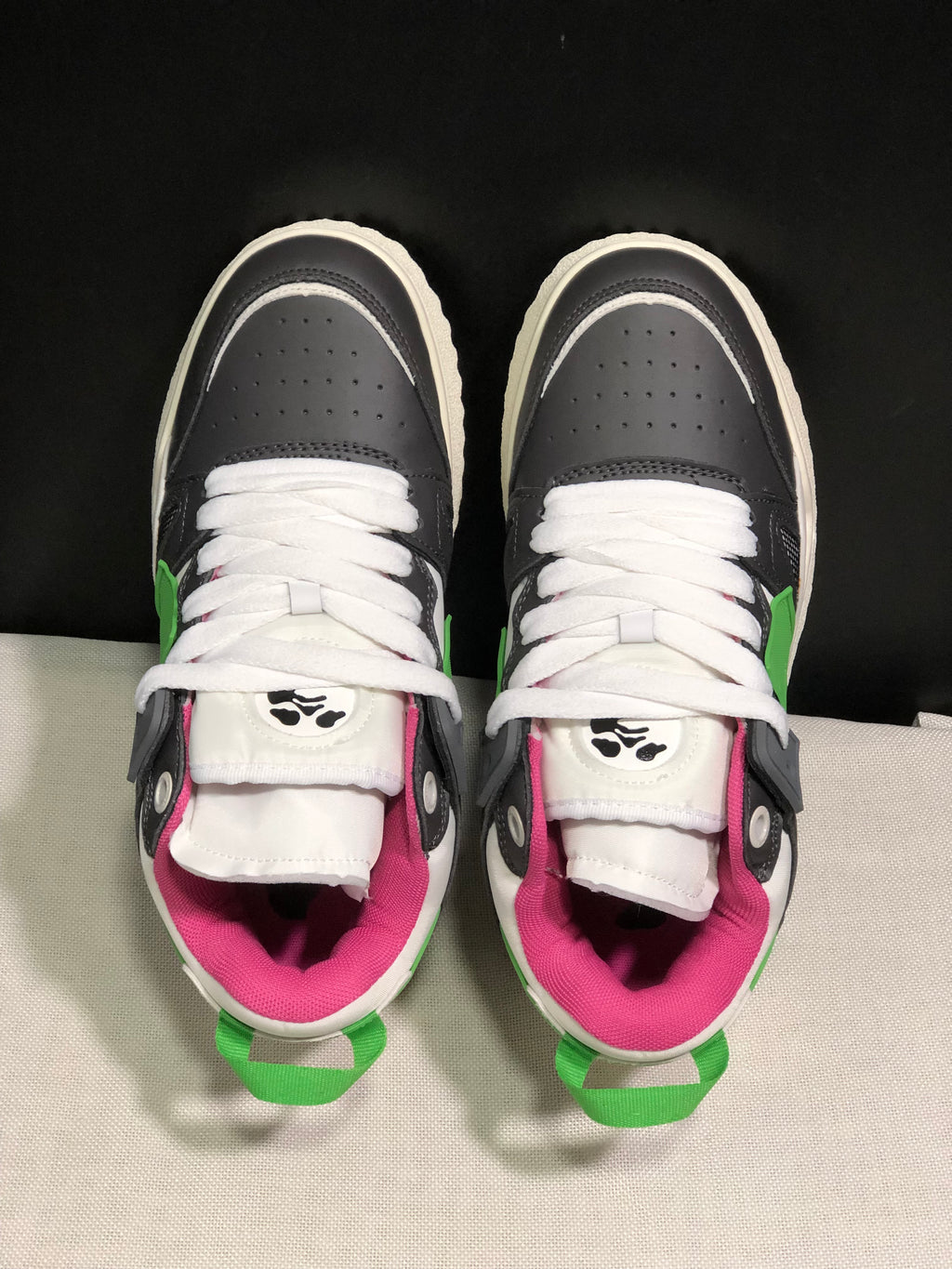 Top view showing white laces, perforated grey toe boxes, layered overlays and pink padded collars.