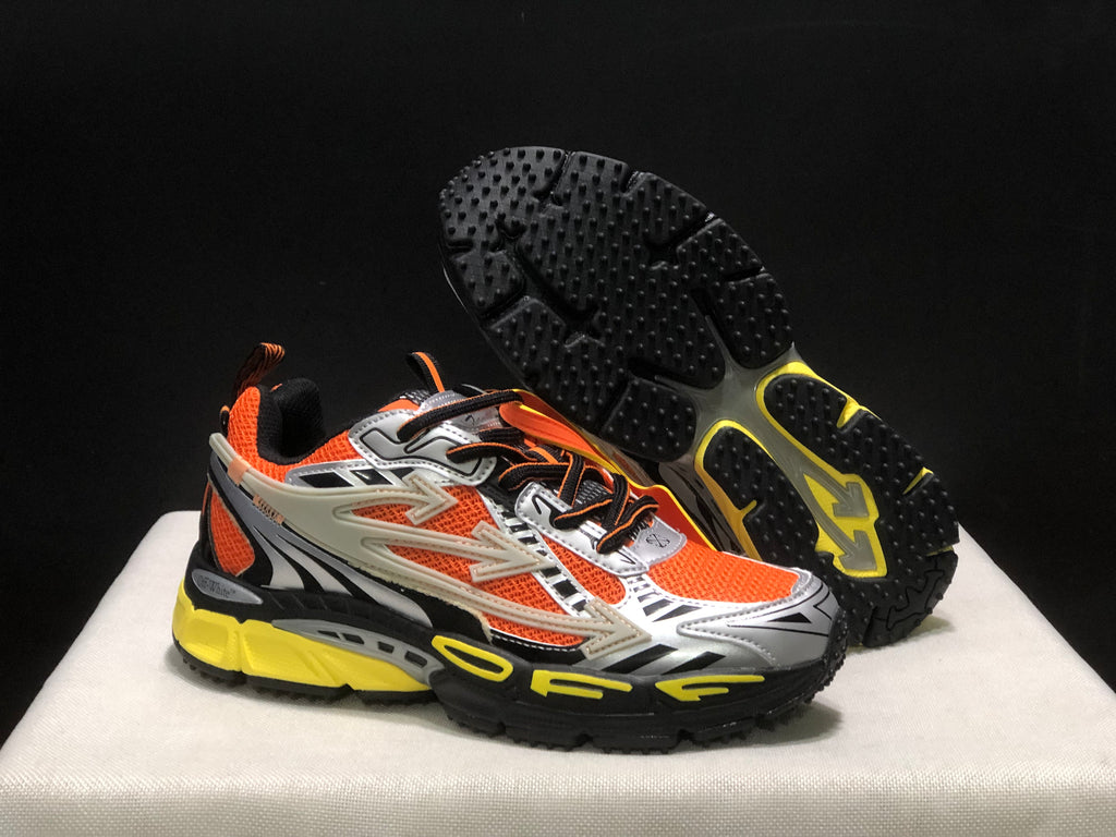 Angled view of the sneakers with one shoe lifted to show the black textured outsole and yellow traction sections.