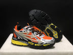 Angled view of the sneakers with one shoe lifted to show the black textured outsole and yellow traction sections.