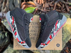 Top view of a pair of black Jordan XXXVIII shoes with red and white details