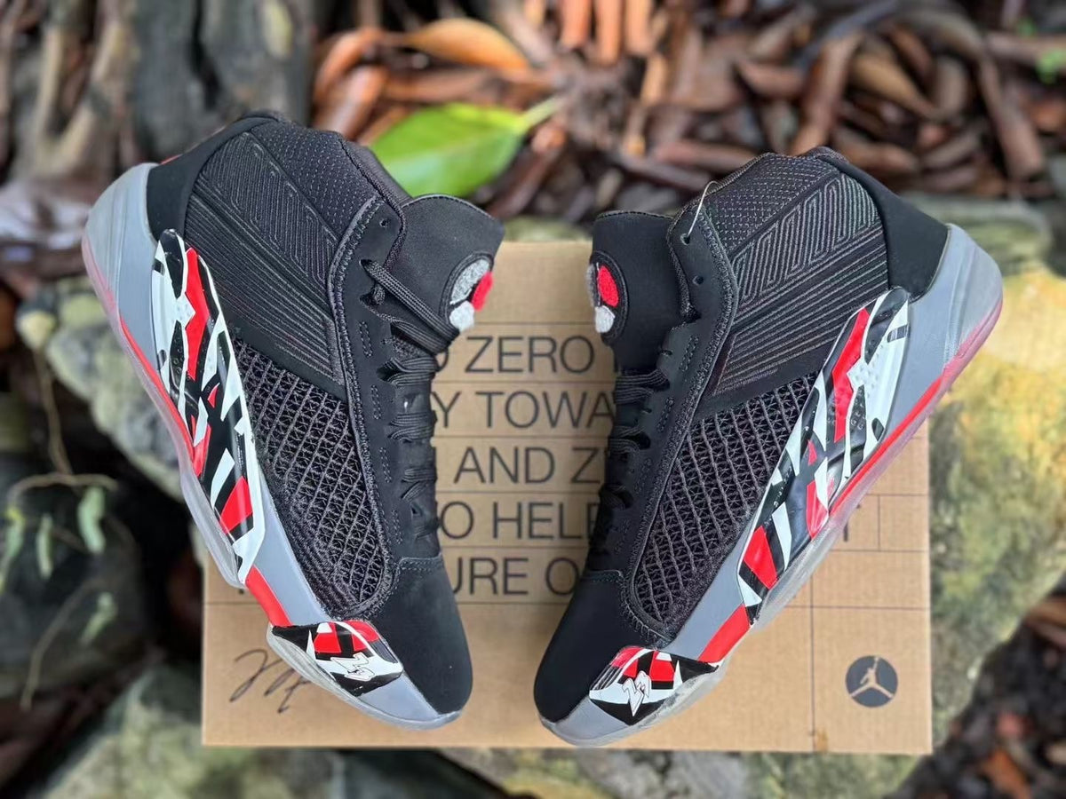 Top view of a pair of black Jordan XXXVIII shoes with red and white details