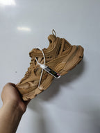 Camel open-panel sneaker held at an angle, showing the layered upper, lace fastening, and sculpted sole.
