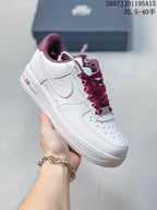 Angled side view of a white Nike low-top sneaker with burgundy laces, Swoosh branding, and textured outsole.
