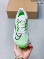 Top view of a white Nike running sneaker with green lace details, black branding and a green outsole tip.